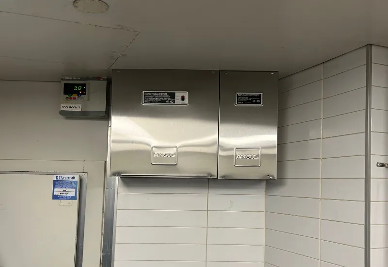 Two stainless steel Ansul control panels mounted on a tiled kitchen wall, part of a commercial kitchen fire suppression and compliance inspection system.
